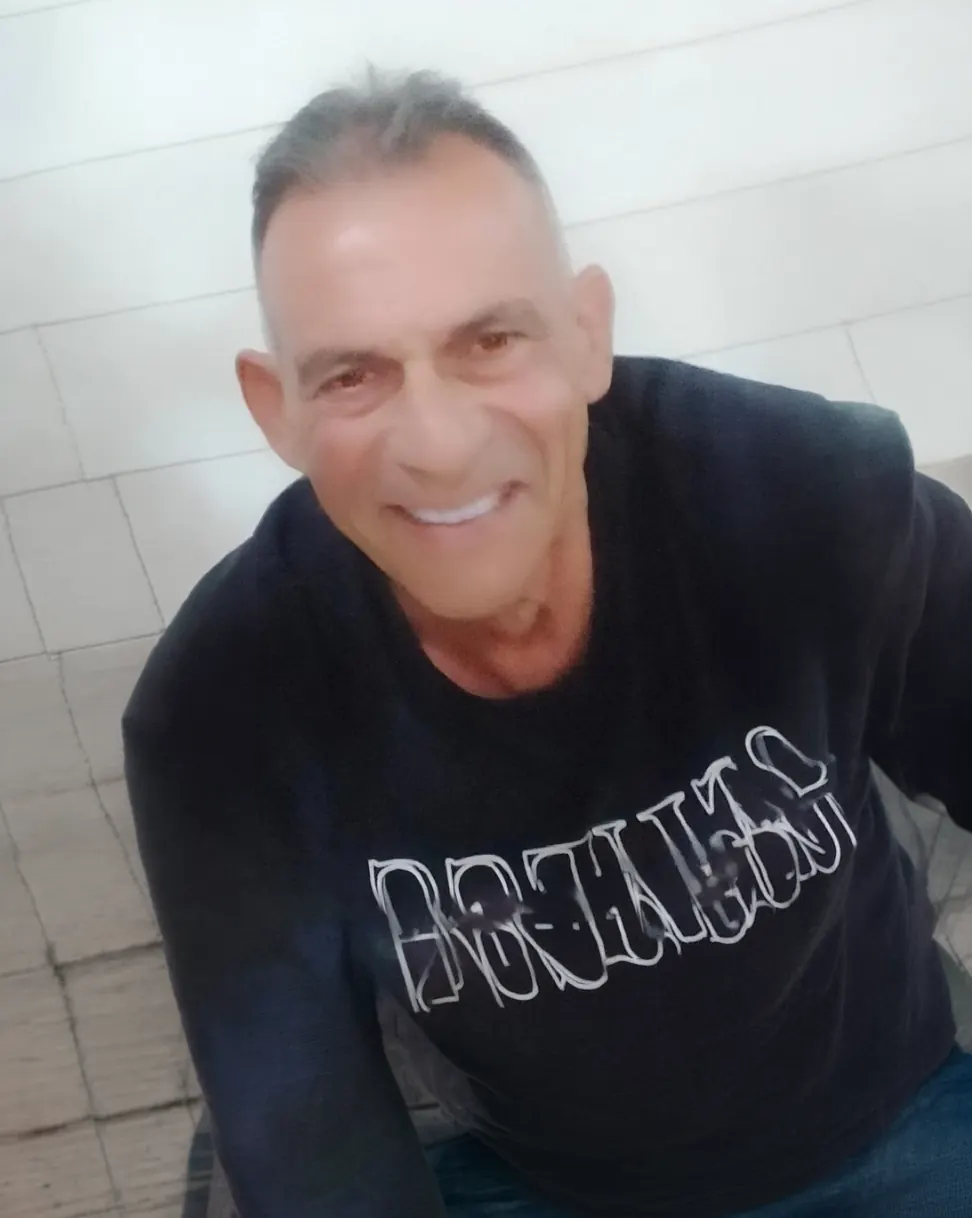 Uomo sorridente con una maglietta nera, fotografato da vicino