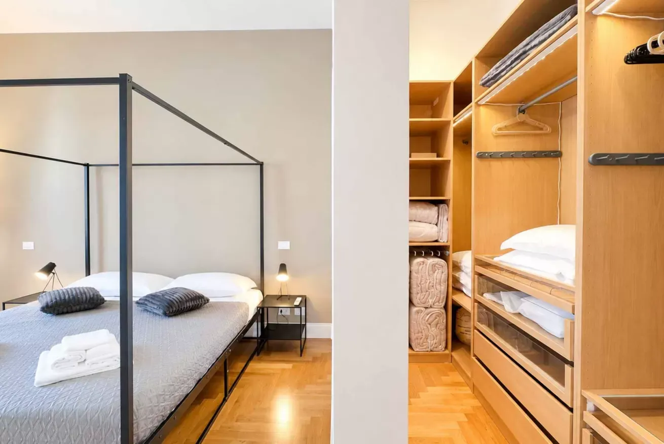 Camera da letto con letto a baldacchino e cabina armadio in legno con biancheria e appendiabiti