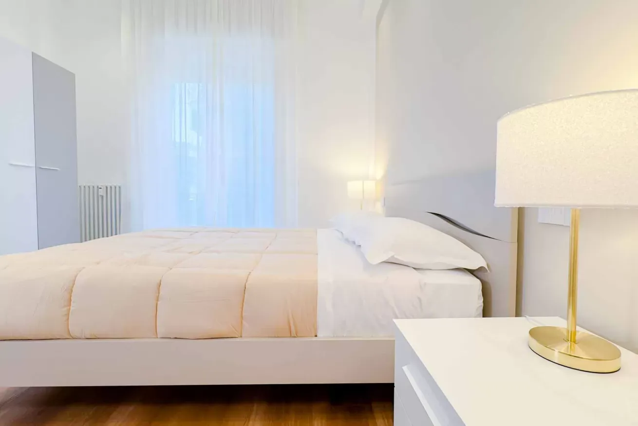 Camera da letto luminosa con letto matrimoniale, comodino e lampada dorata