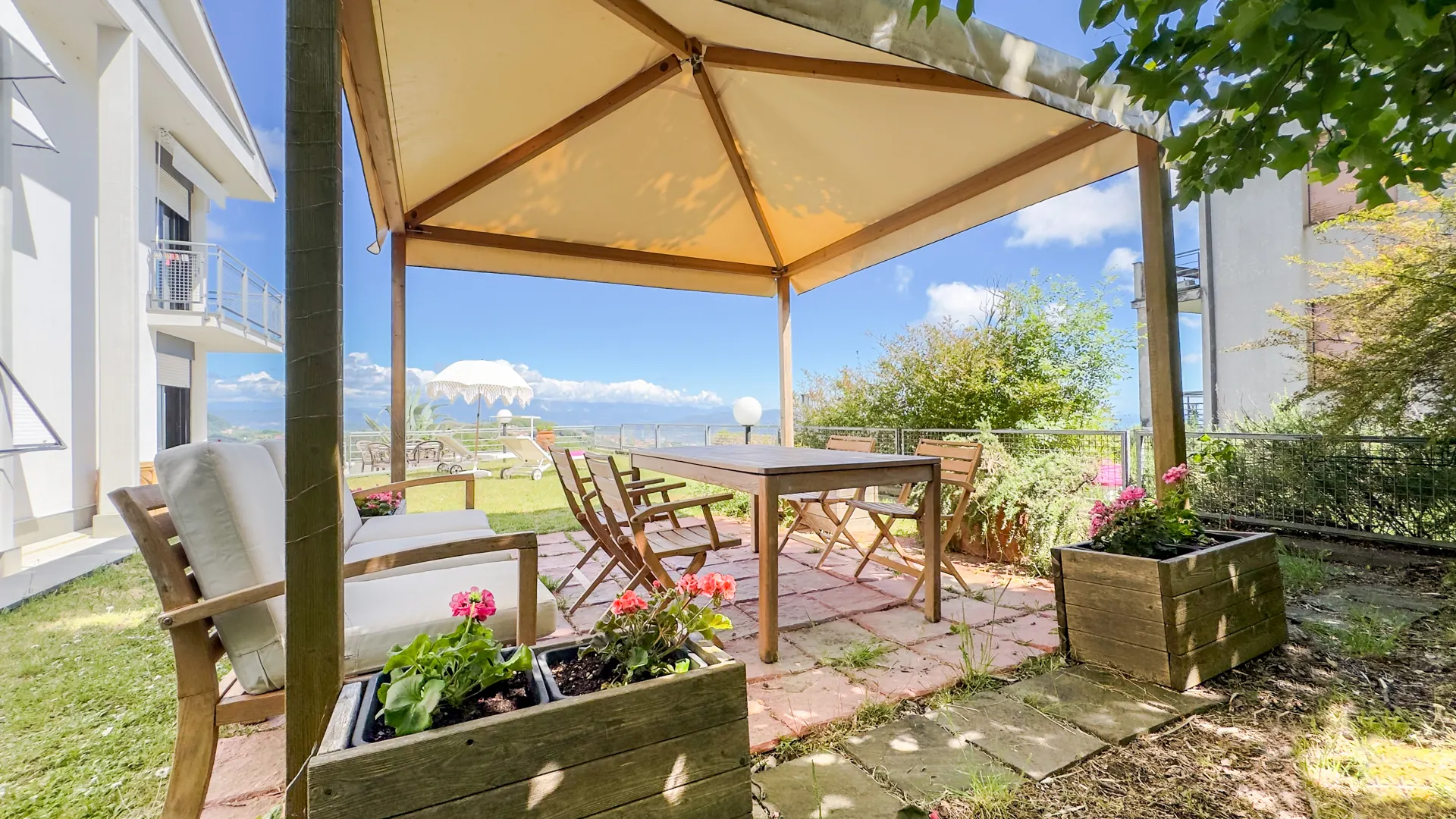 Terrazza con pergola, tavolo e sedie in legno, fioriere e vista panoramica sulle montagne