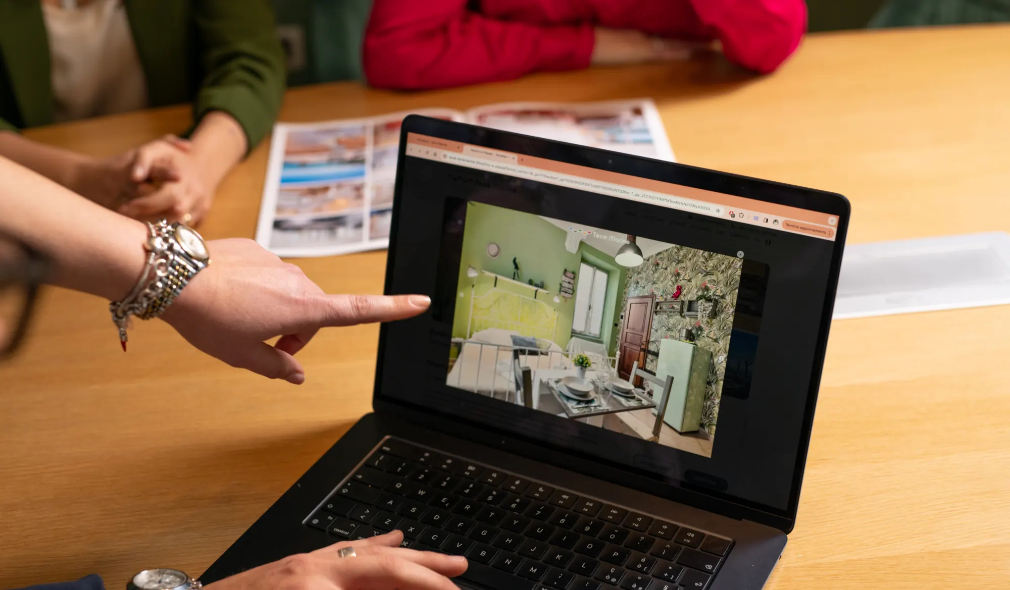 Una persona indica la foto di un soggiorno visualizzata su un laptop durante una discussione
