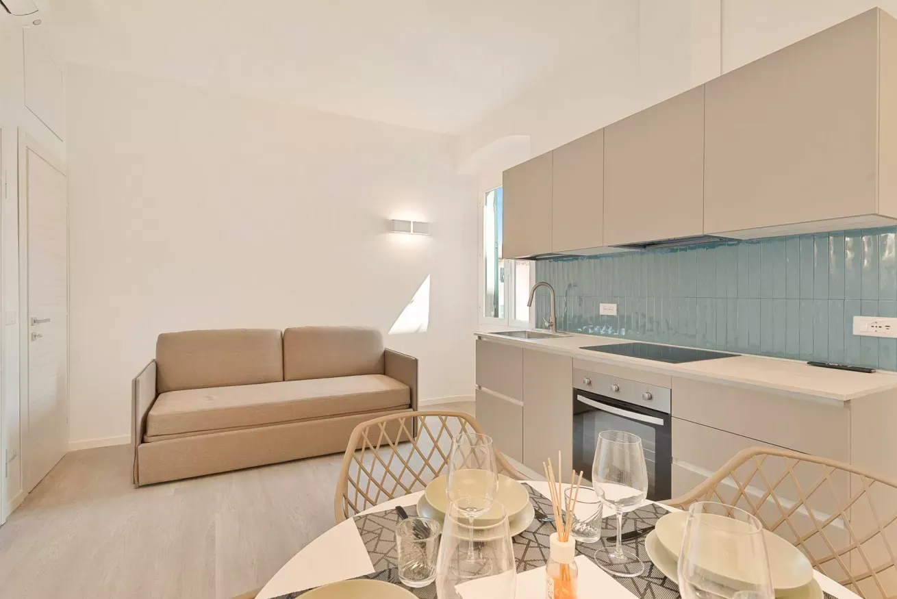 Soggiorno open space con divano, cucina moderna e tavolo da pranzo apparecchiato