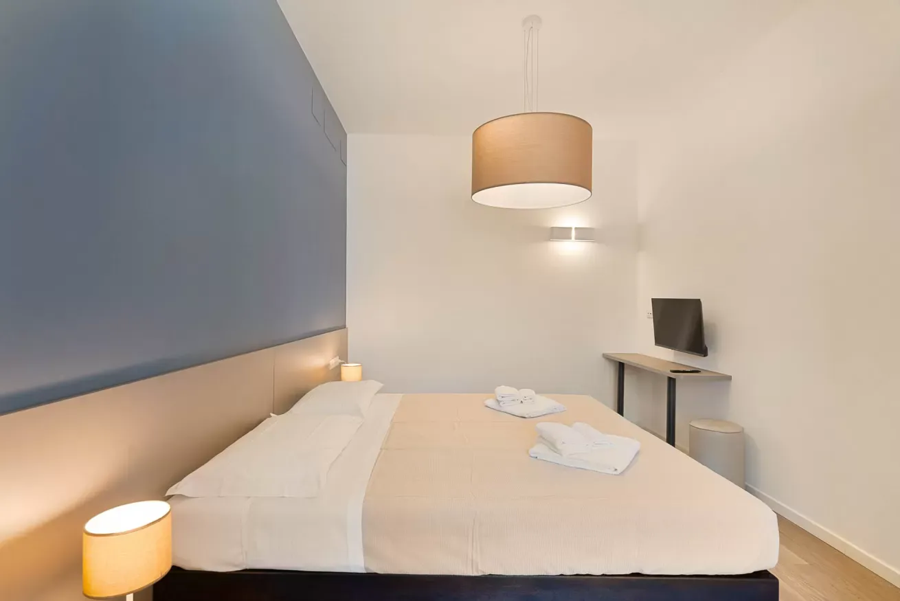 Camera da letto moderna con letto matrimoniale, televisore a parete e illuminazione calda